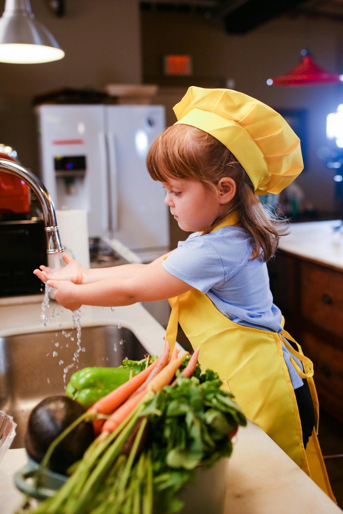 Little girl washing hands in kitchen sink